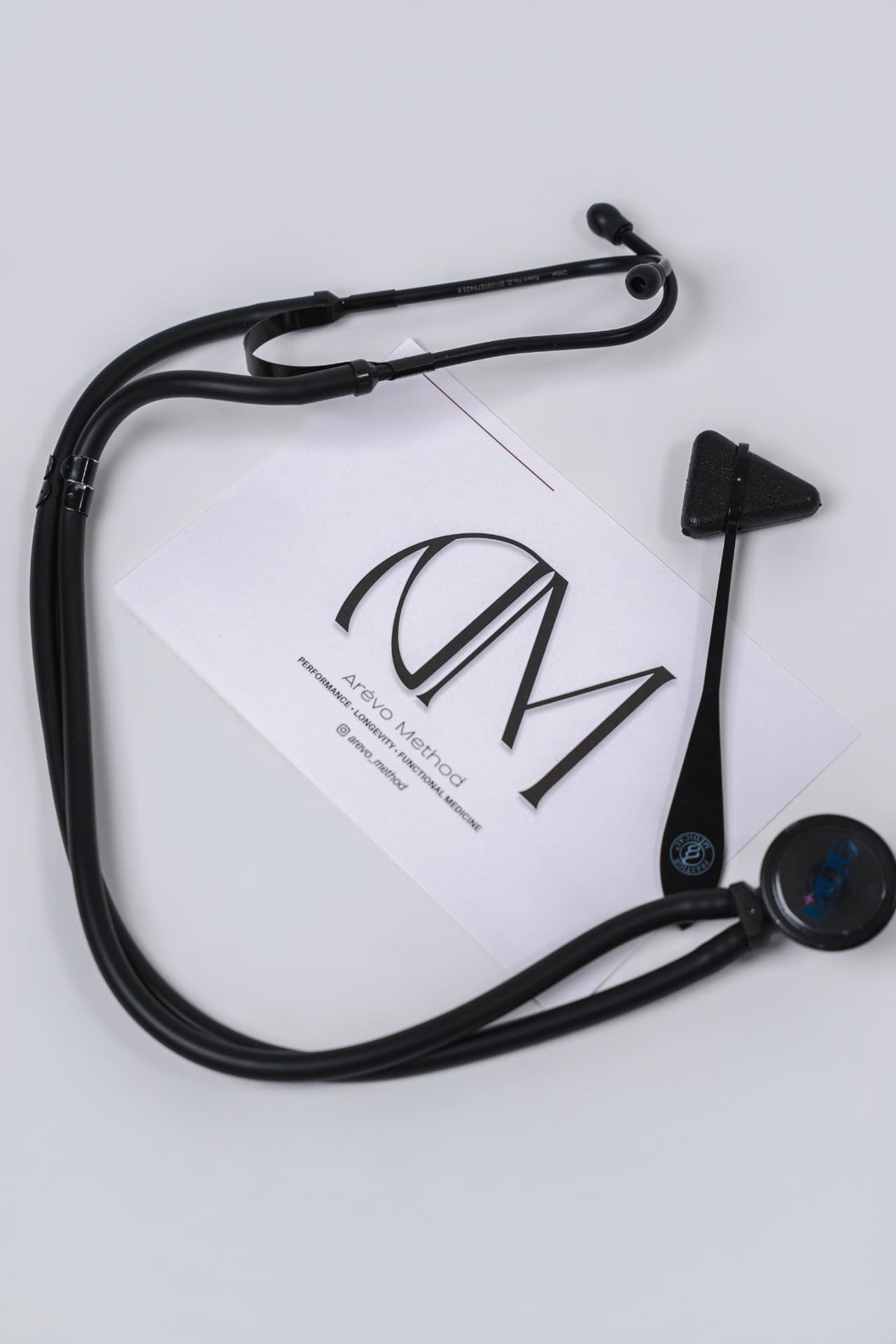 Arévo Method card beside a stethoscope and reflex hammer
